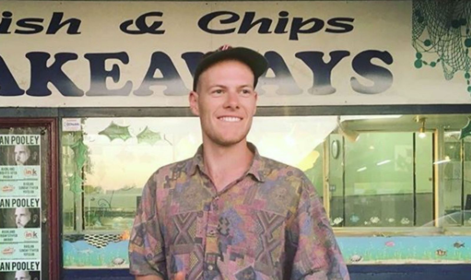 Cory Champion stands outside a fish and chip shop.