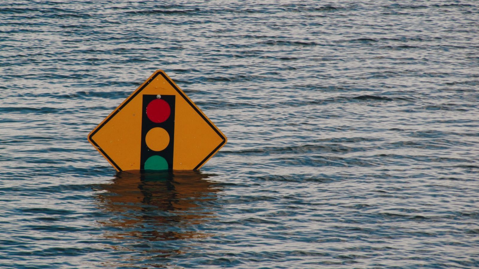 A street sign emerging from the water on a flooded street 