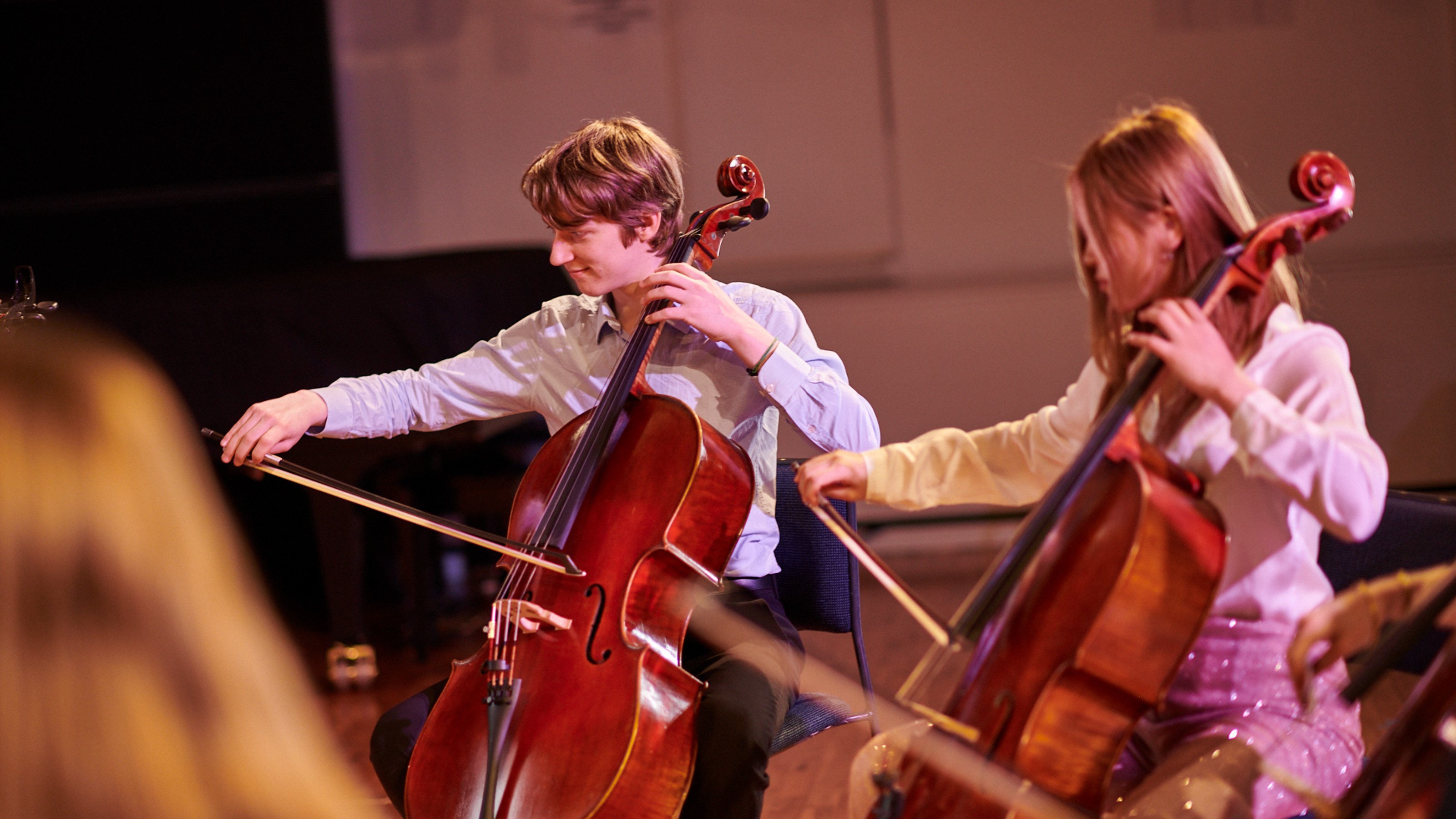 to people seated playing cellos