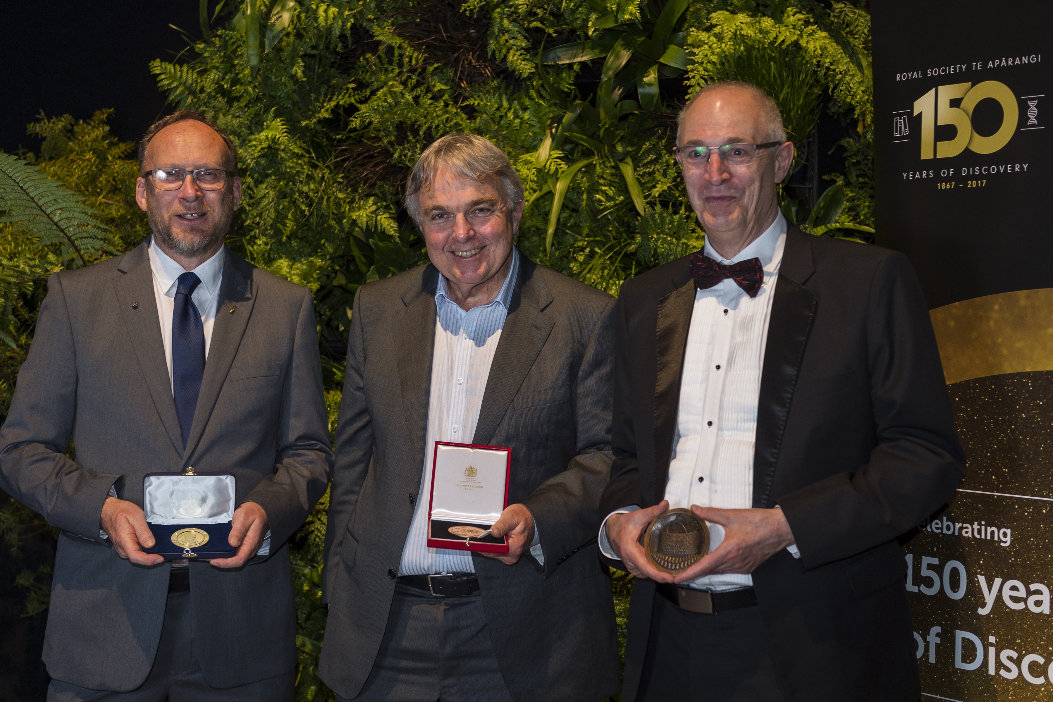 Three winners of rutherford awards stand in a row holding their medals, From left: Professor Colin Wilson, Professor Peter Tyler and Emeritus Professor Laurie Bauer.