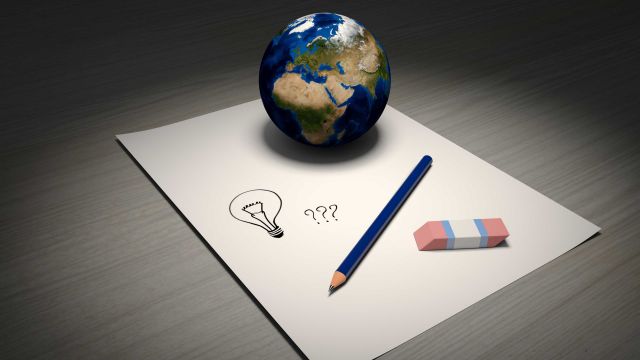 A small globe with paper, pen and question mark.