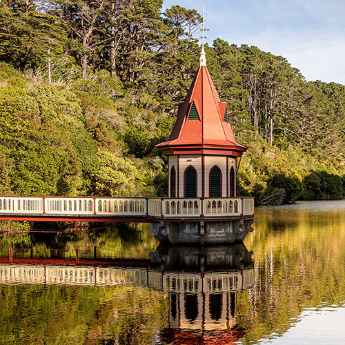 The historic pumphouse at Zealandia—a small house-like structure with a pointed top sitting over water.