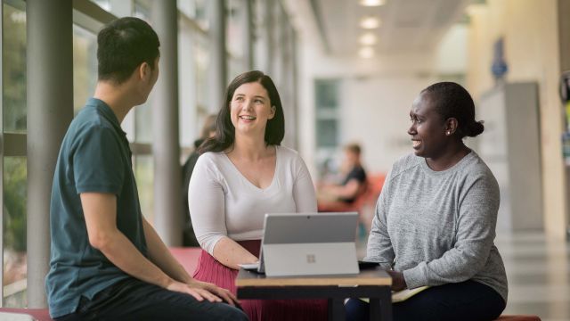 A group of students chat together on campus