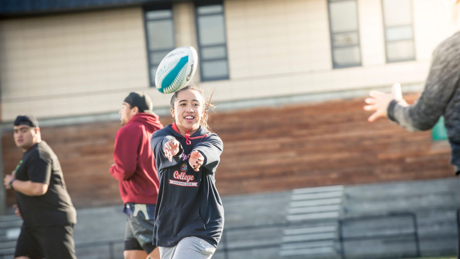 Action shot of female student throwing rugby ball. 
