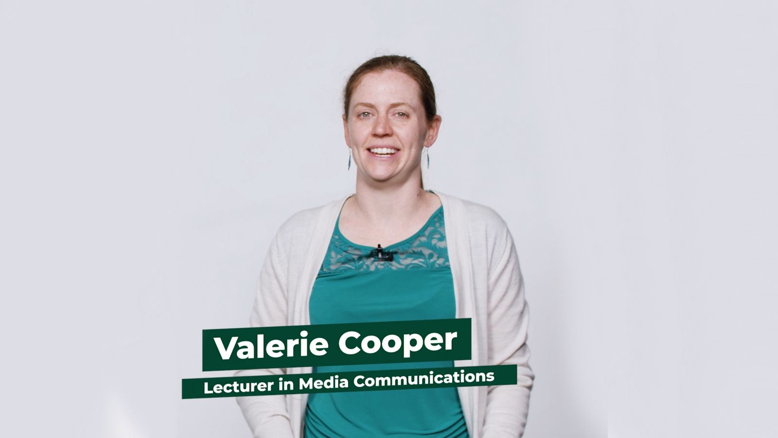 Dr Valerie Cooper stands facing the camera against a white backdrop