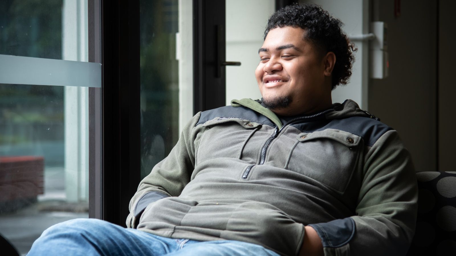 A student sitting relaxed with their feet up, looking content and reflective.