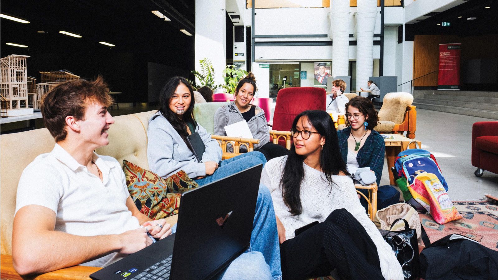 A group of architecture students relaxing in the atrium of the Te Aro School of Architecture and Design