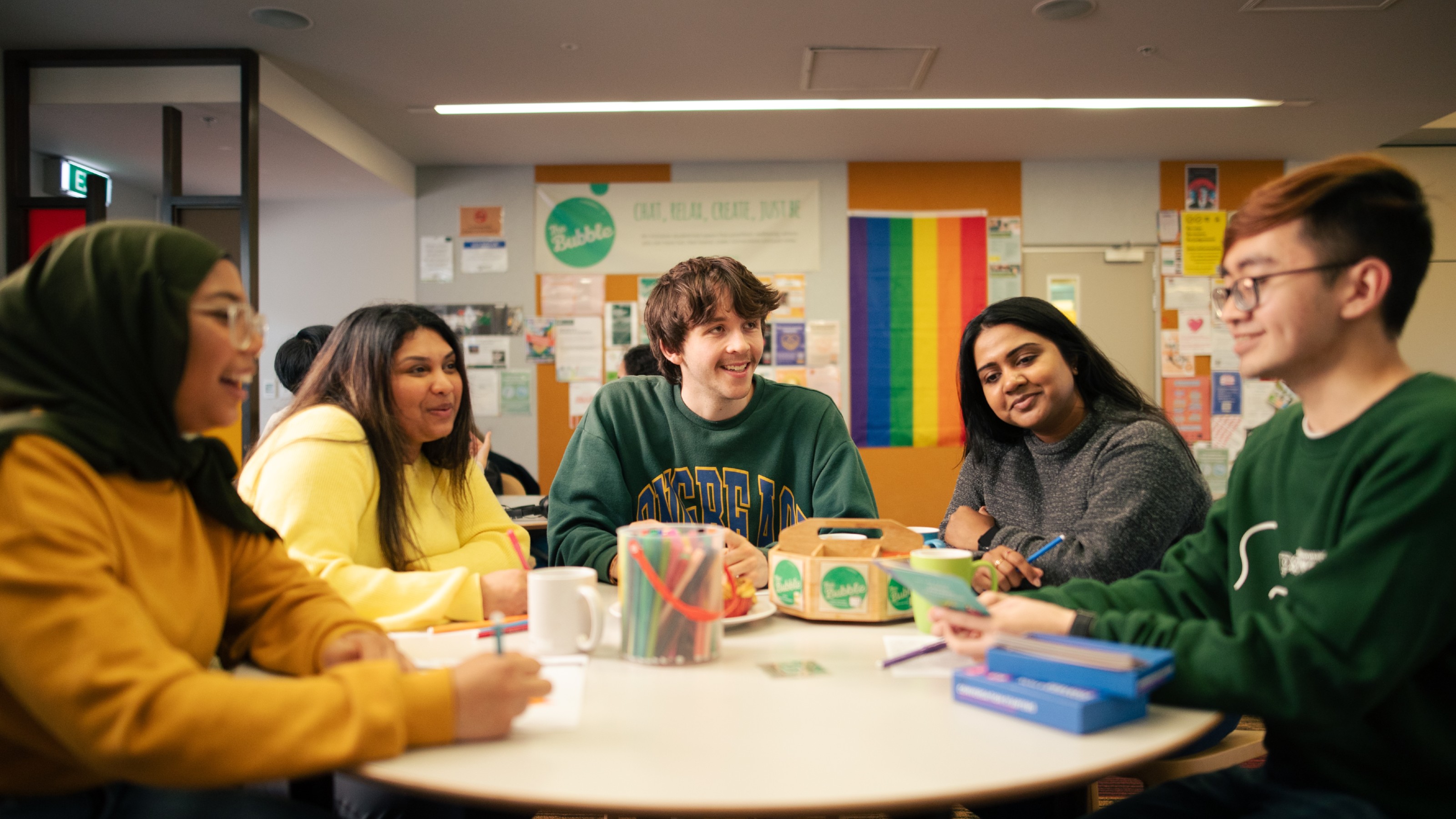Five students talking and colouring at a table in The Bubble.