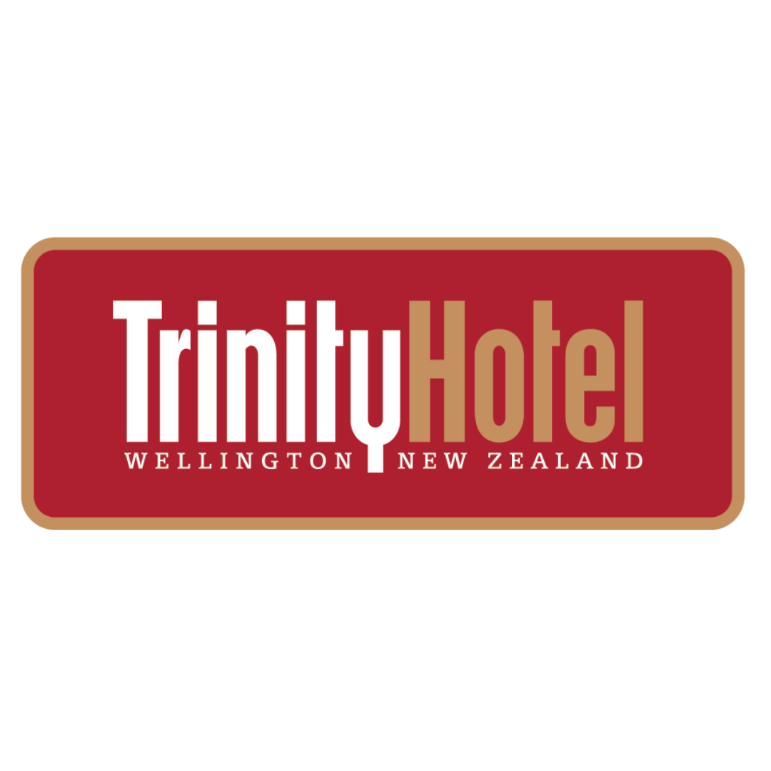 This is the Trinity Hotel logo with a red rounded rectangle, with gold around the edges. The words 'Trinity Hotel Wellington New Zealand' are inside the rounded rectangle, all of the words white apart from 'hotel', which is in gold. 'Trinity Hotel' is large and 'Wellington New Zealand' is in smaller text below.