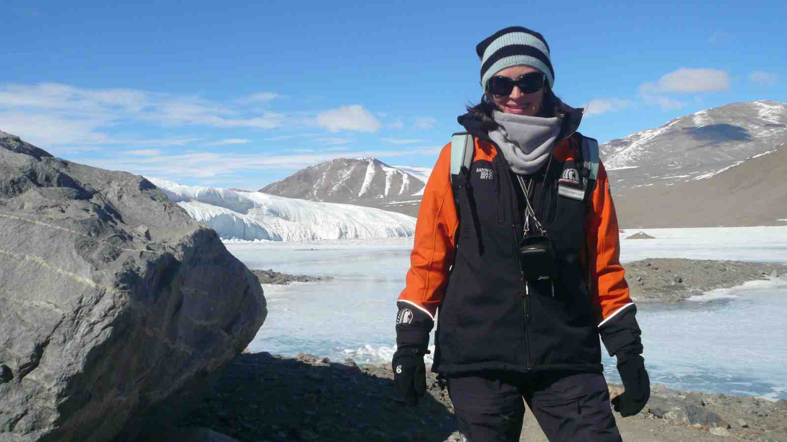 Rebecca Priestley stands in front of mountains and a glacier in Antarctica.