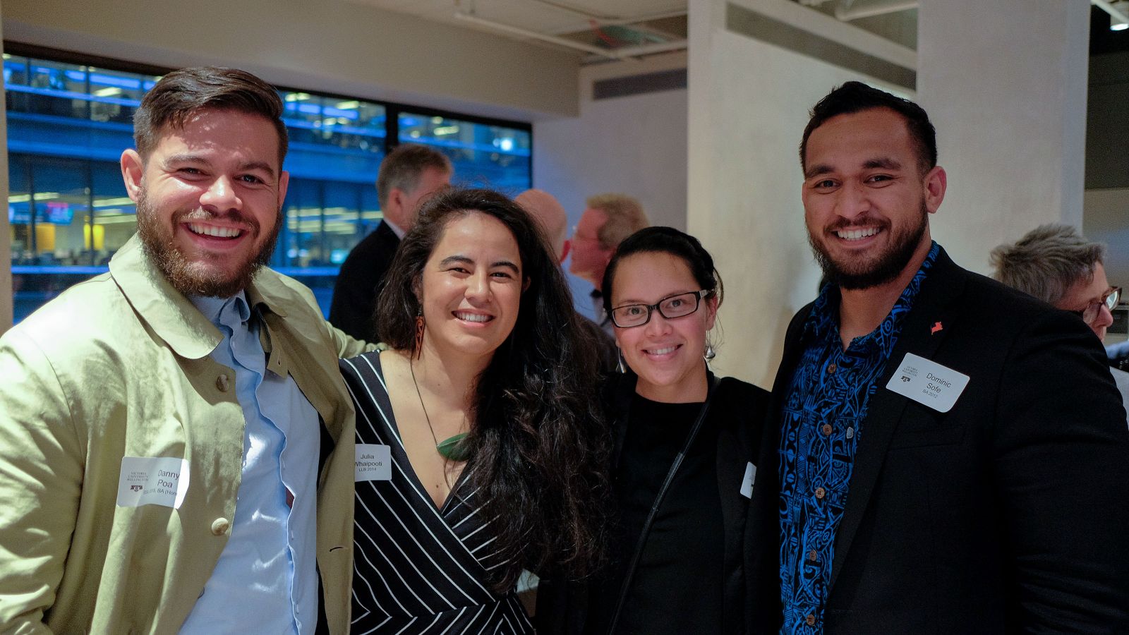 Four alumni—two men and two women—smile for the camera at an alumni event.