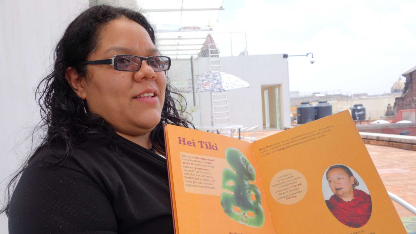 Monserrat Navarro holding a book resource she developed for Museo Nacional de las Culturas's showing of E Tū Ake.