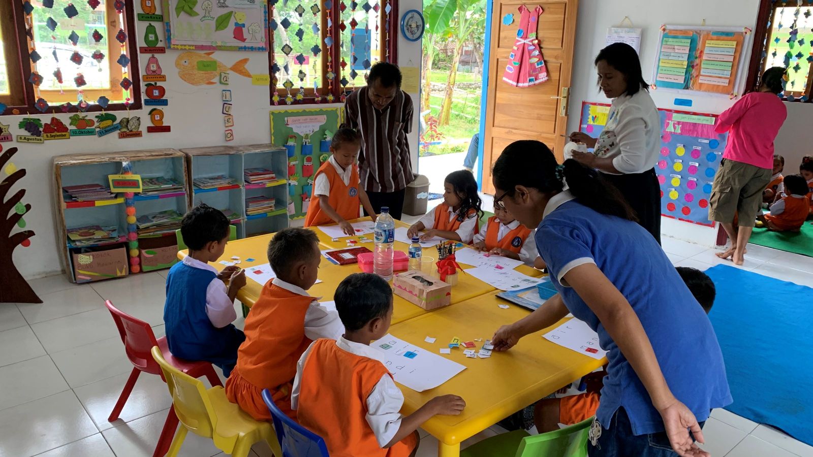 Children working at table in a colourful classroom.