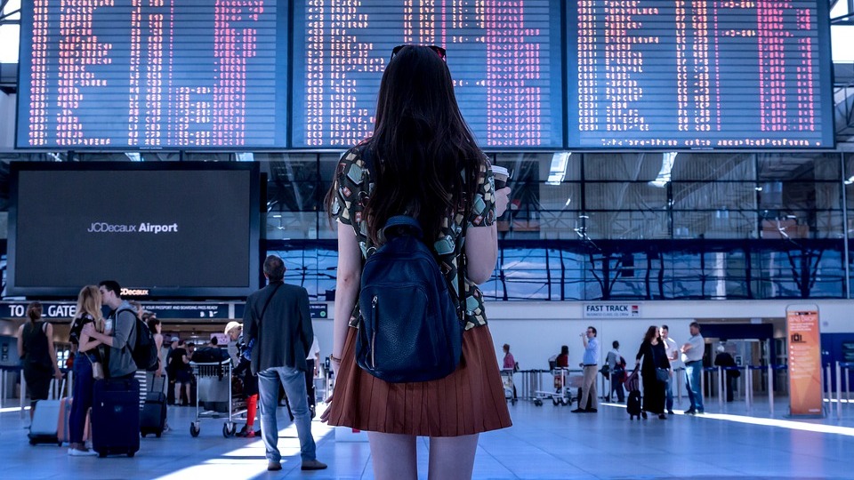 Young woman looking toward departure board at an airport.