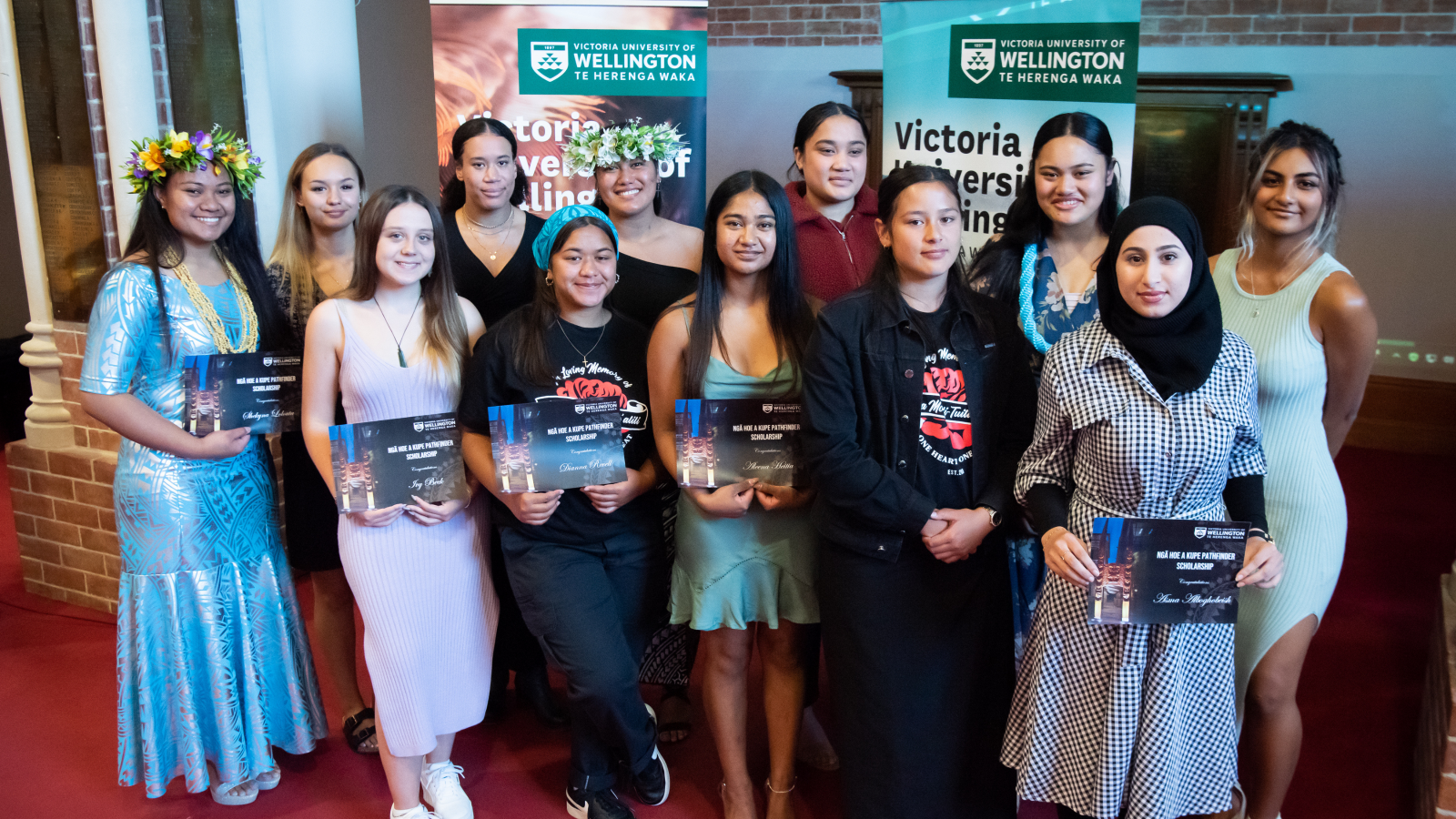 12 young women with certificates, some with flower lei in their hair