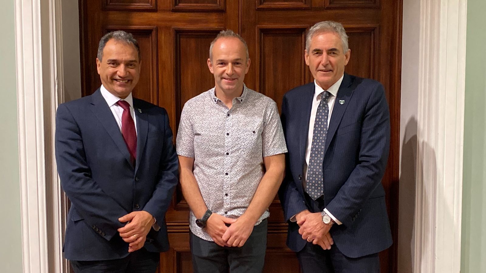 James Bell inaugural lecture Professors Ehsan Mesbahi, James Bell and Grant Guilford standing in front of a wooden doorway.
