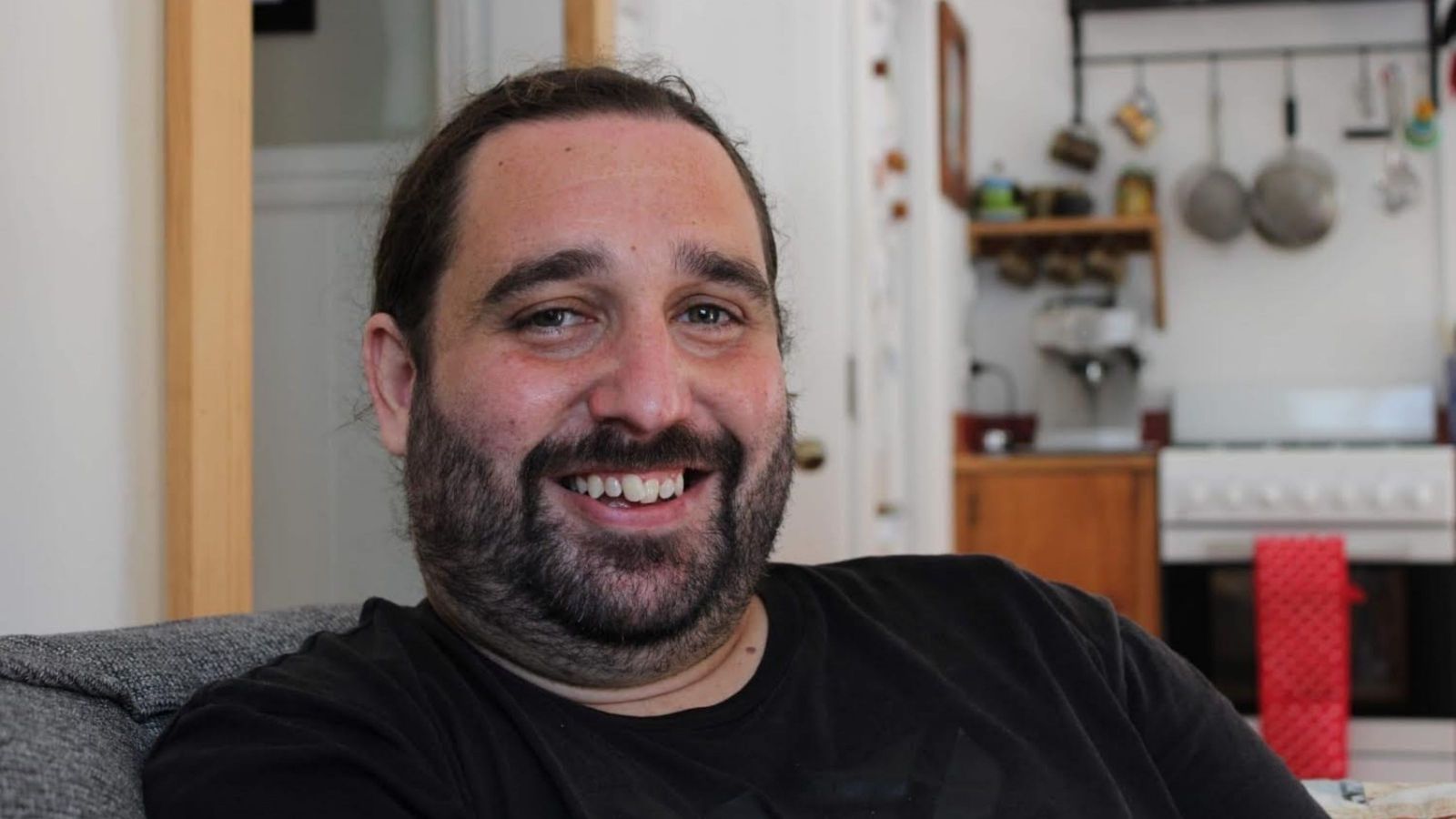 Man with stubble smiling with kitchen in background