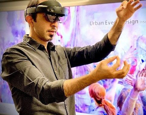 A man in a black shirt, wearing a VR headset, holds an imaginary thread between the fingers of each hand.