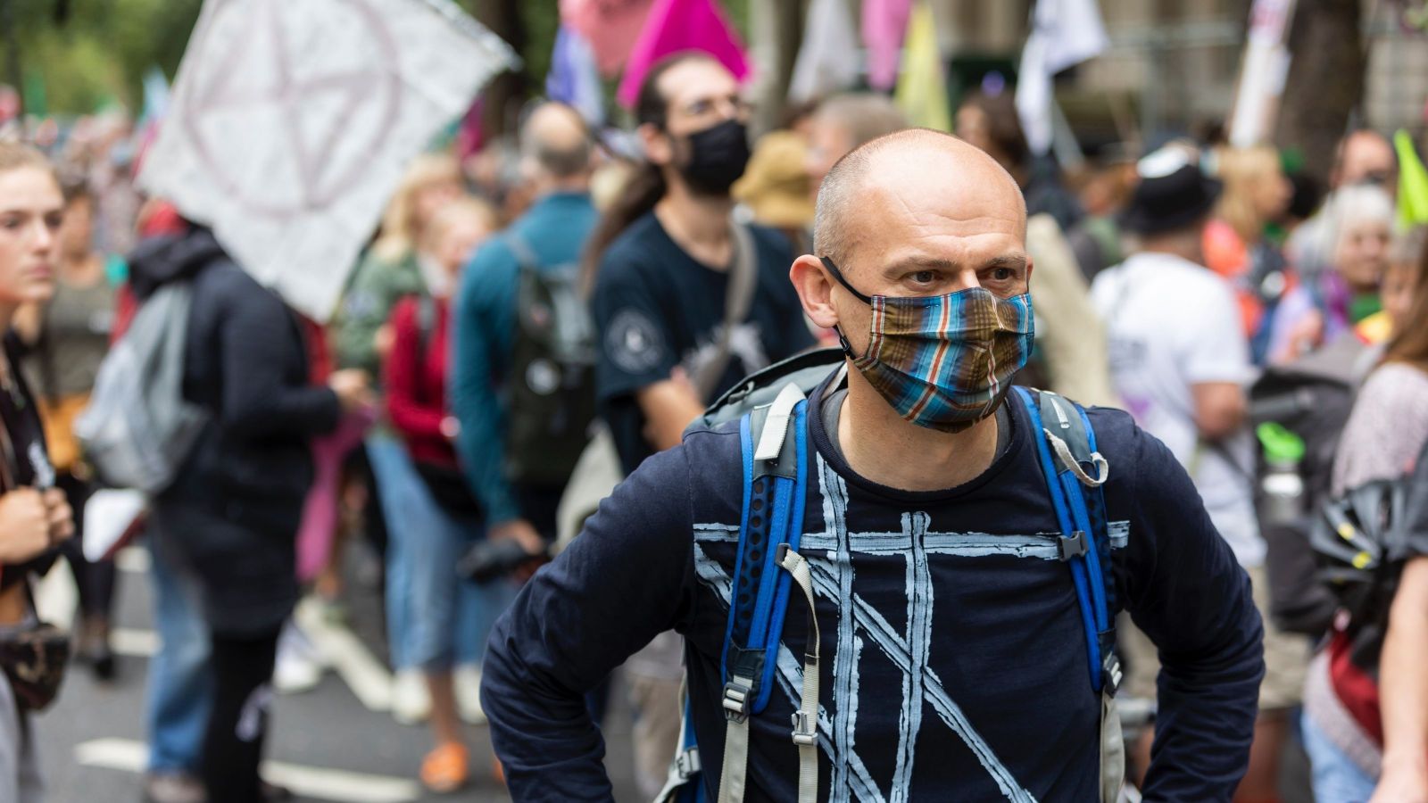 man with mask at front of crowd with extinction rebellion symbol in background