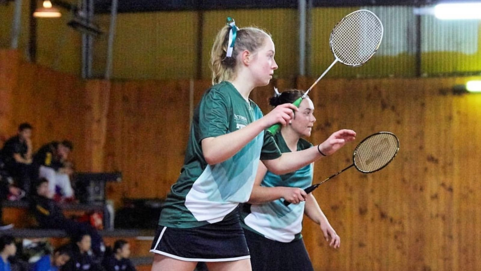 Two badminton players in game with rackets up.