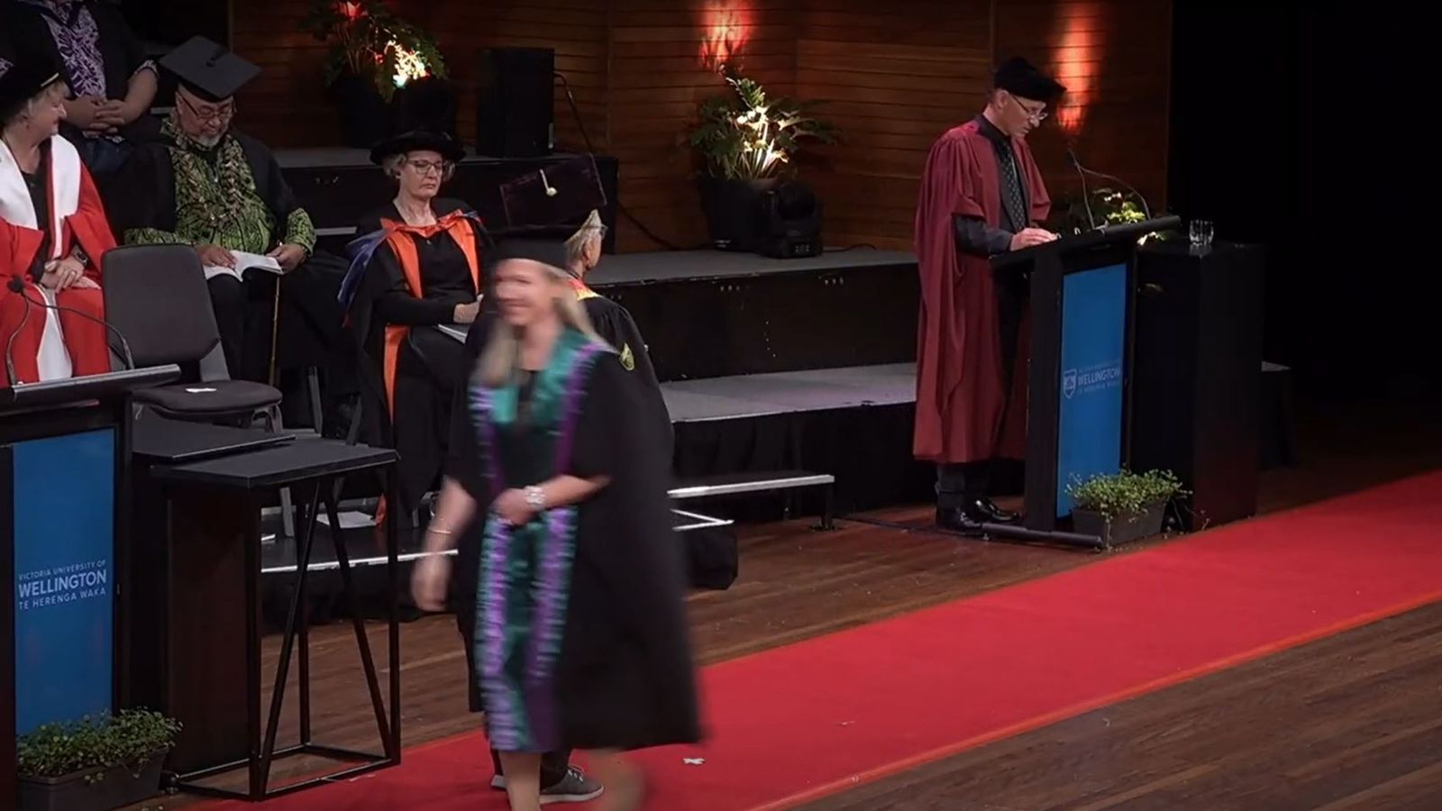 A graduate walking off the stage smiling.