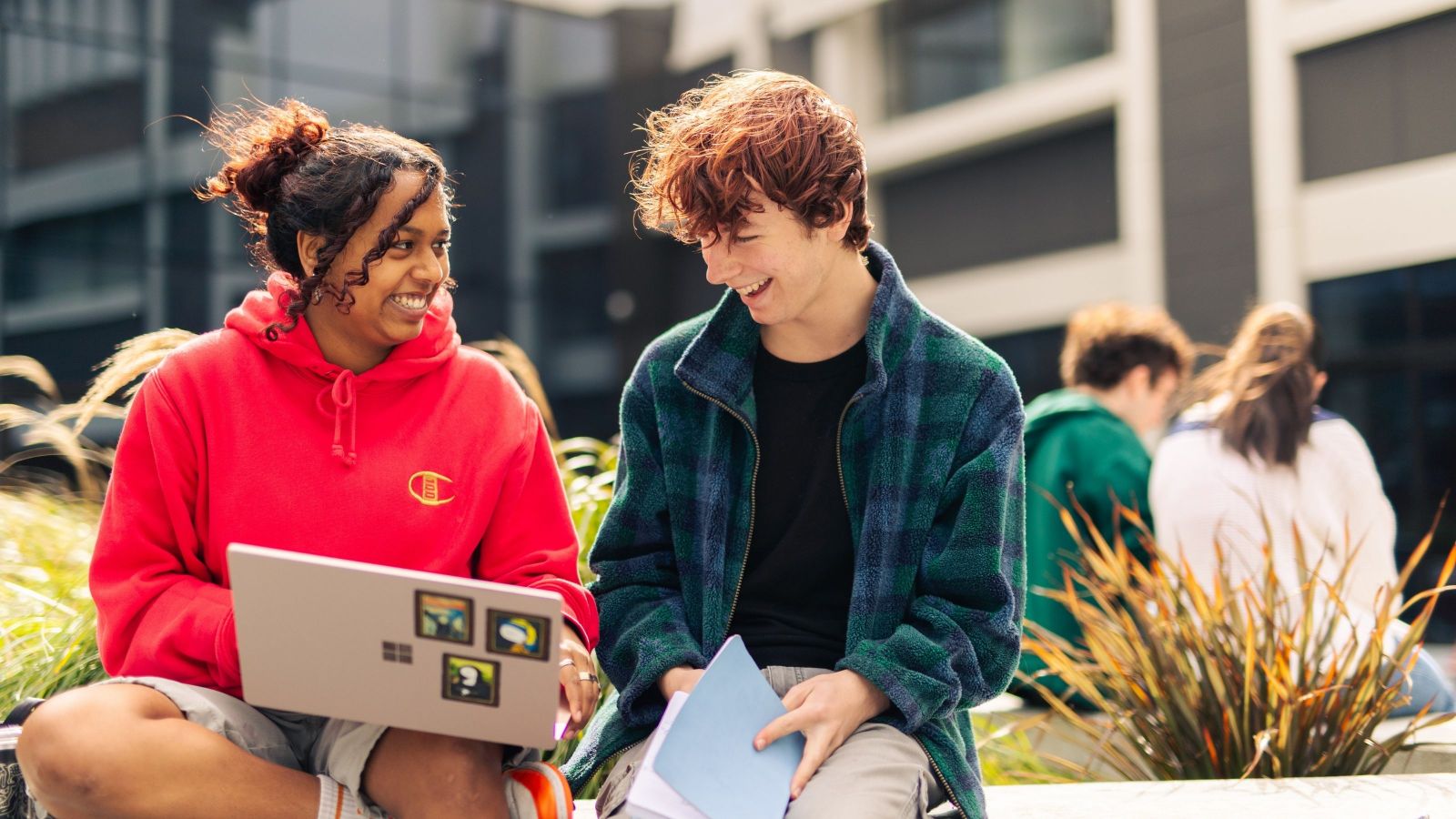 Students sitting outside and looking at the laptop