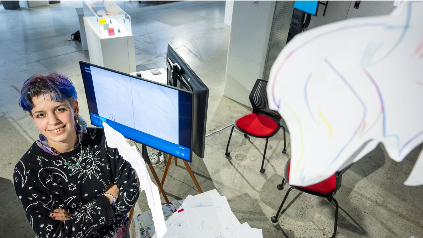 A student stands in front of her display at the 2025 Reframe design exhibition at Te Aro campus