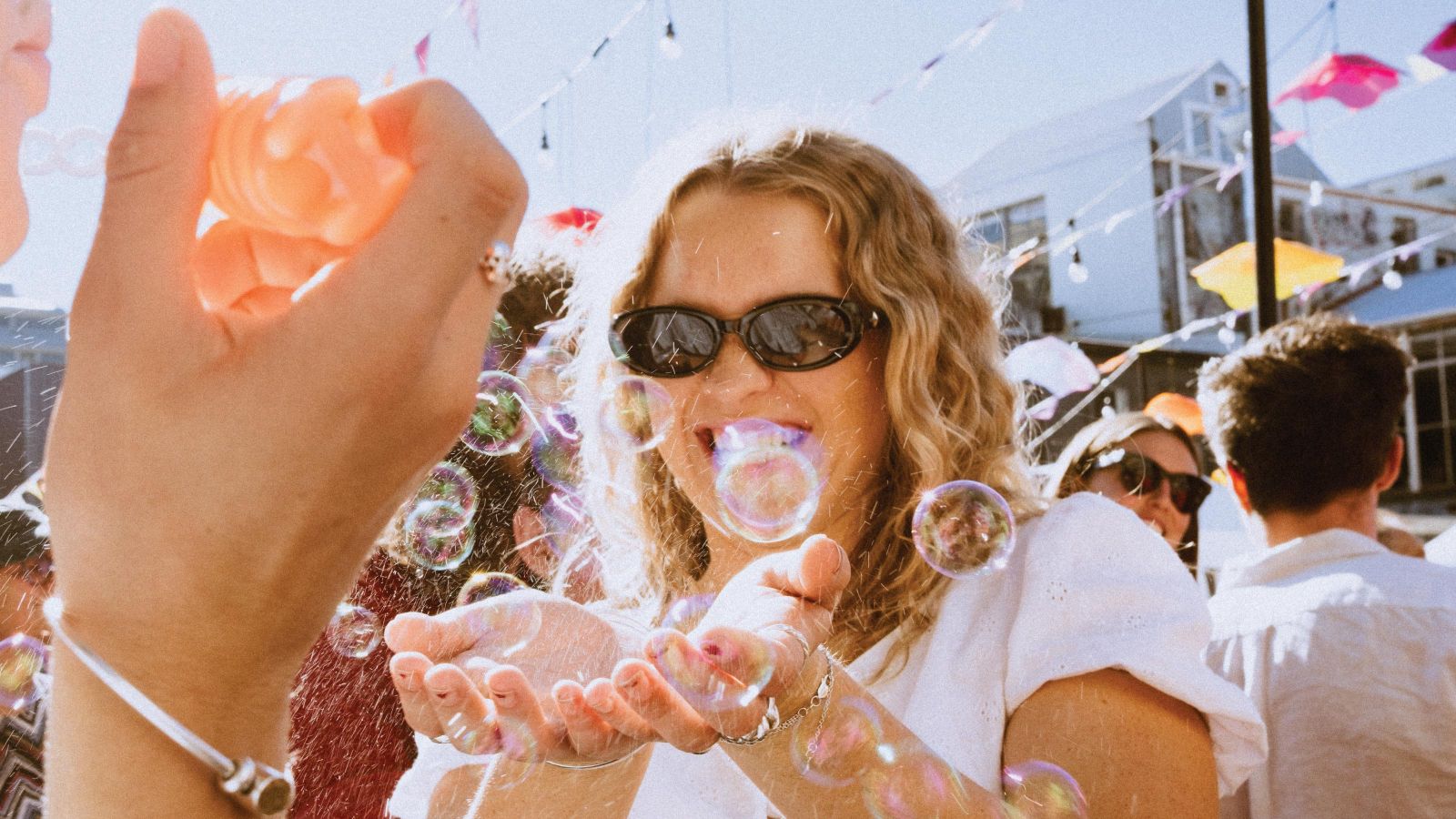 Student wearing sunglasses with cupped hands trying to catch a bubble