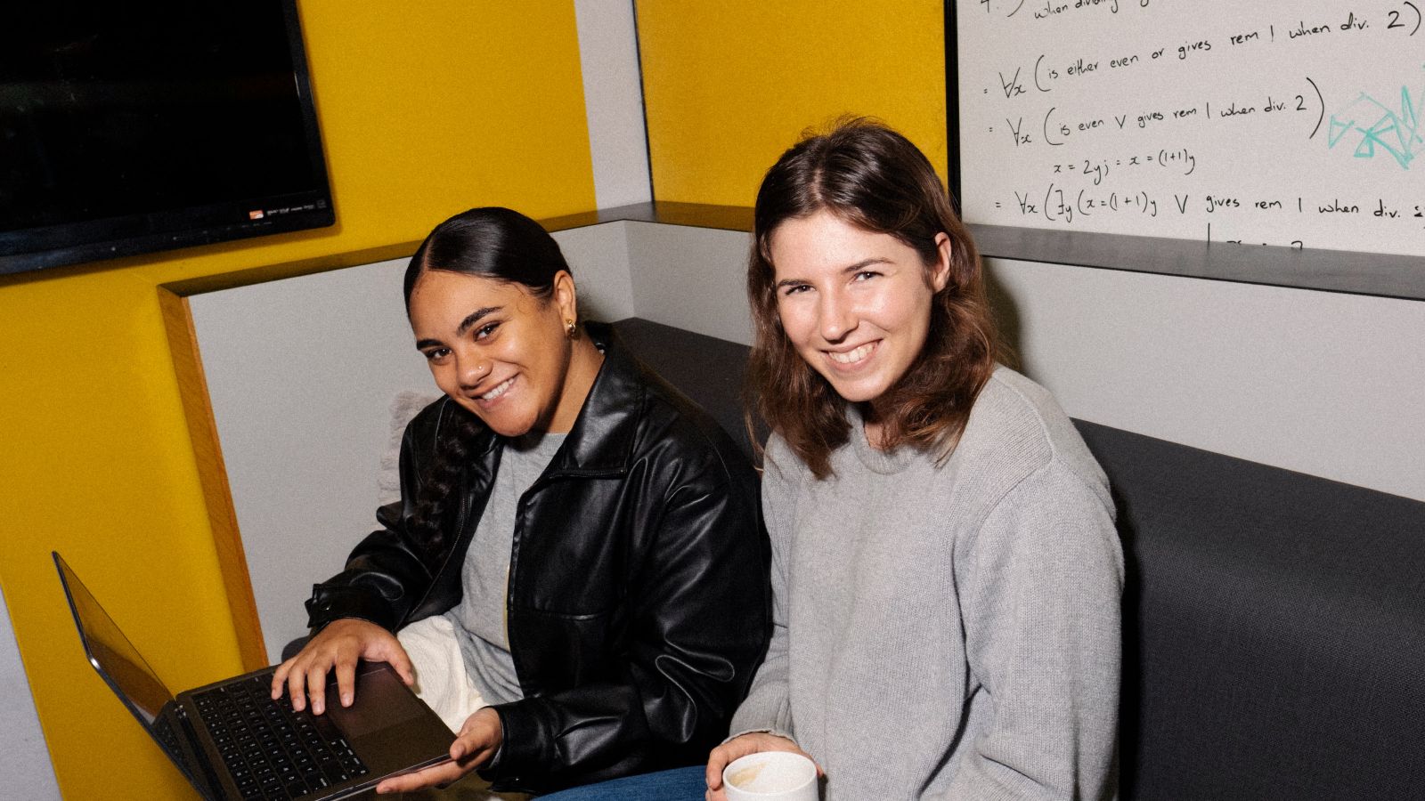 two students studying in the hub at campus while drinking coffee