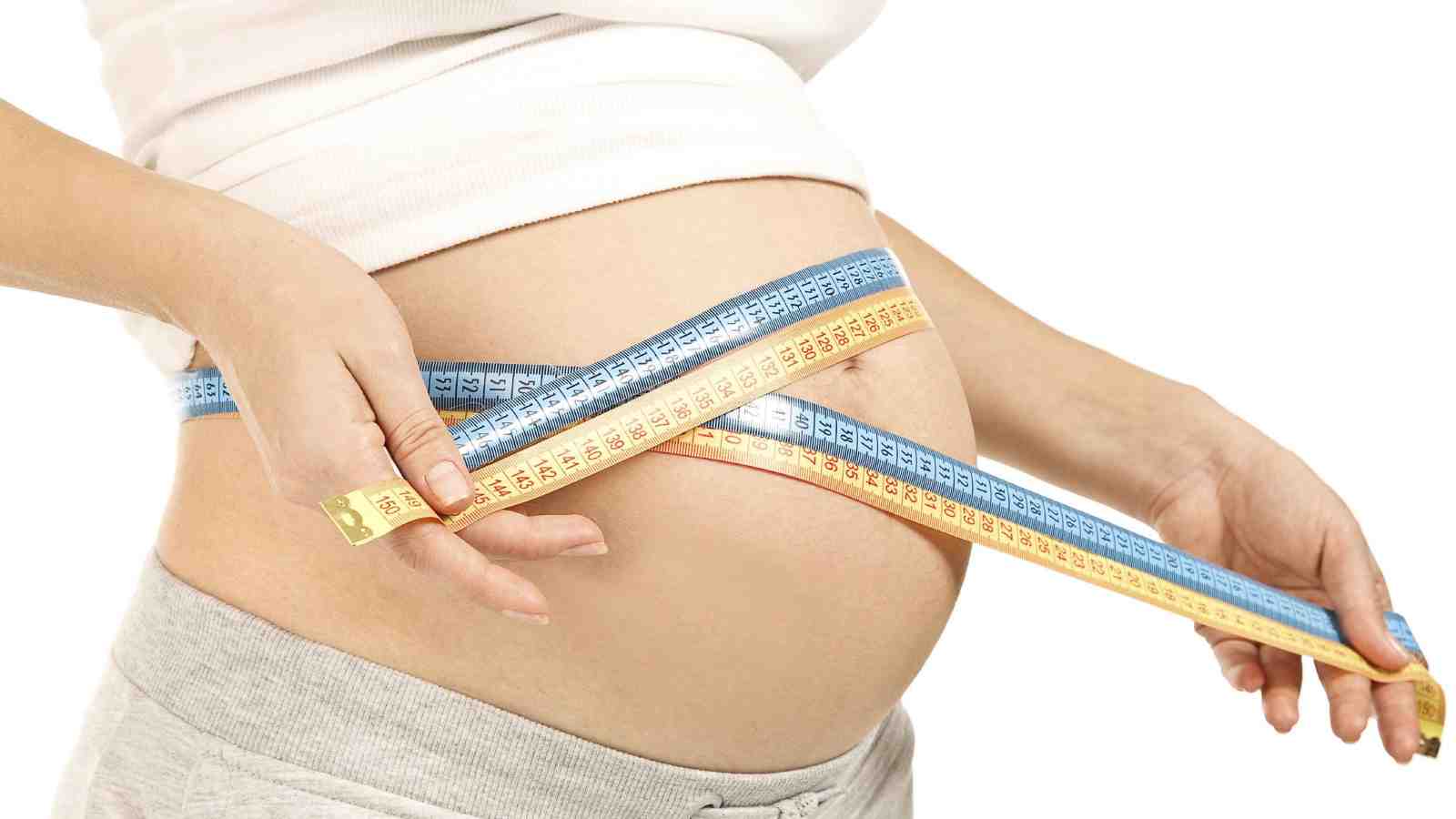 A pregnant woman measuring her abdomen.