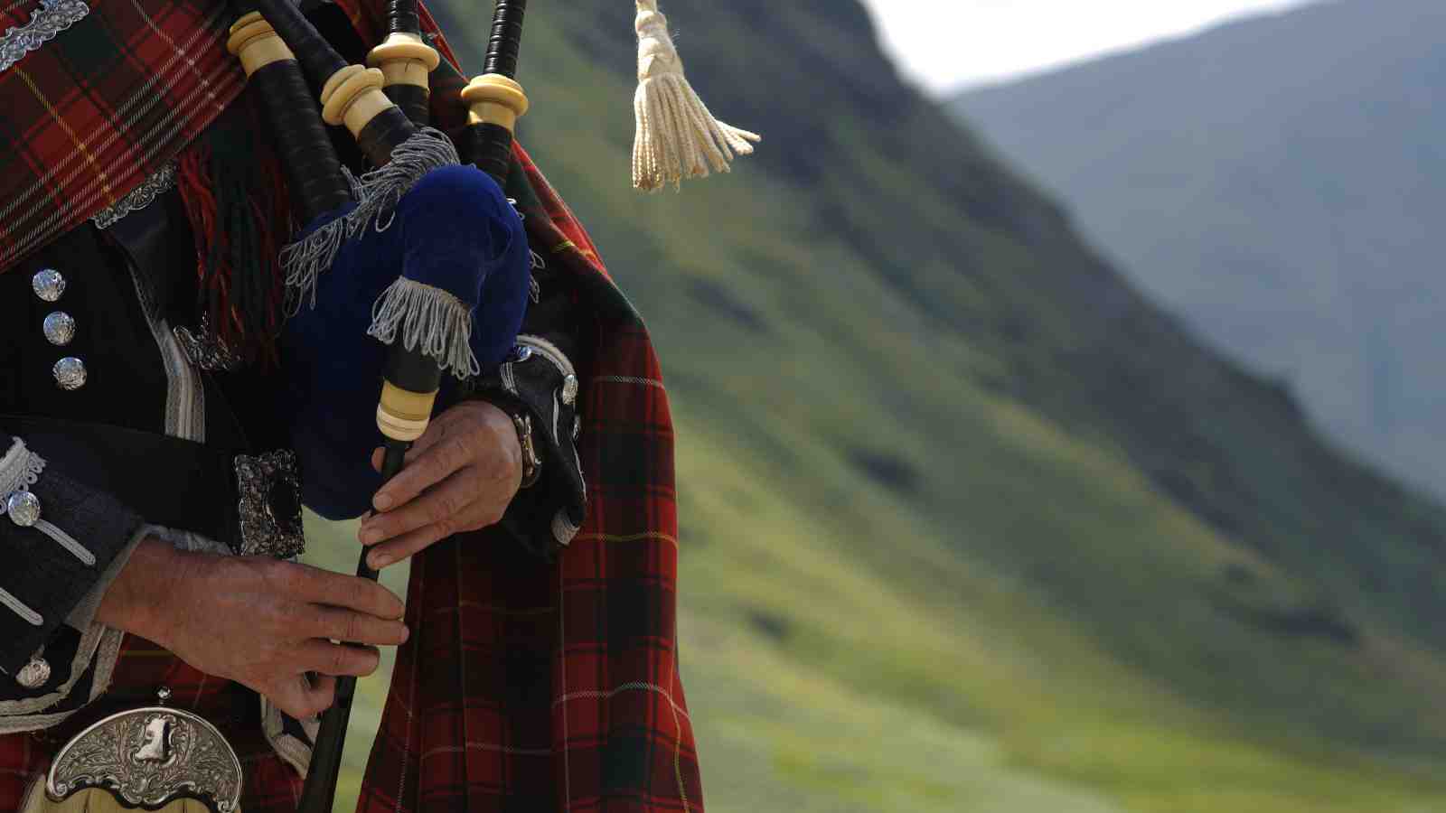 Scottish bagpiper with Scottish countryside in background
