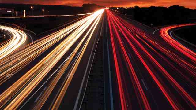 A time-lapse photo of a busy highway in the evening.