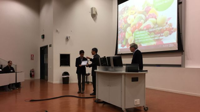 Conference photo – three men stand at the front of a lecture hall.