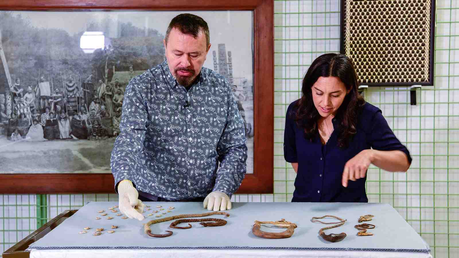 Filming at Te Papa for MOOC Dr Maria Bargh and a Te Papa staff member bending over items on a table.