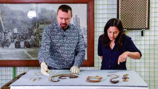 Dr Maria Bargh and a Te Papa staff member bending over items on a table.