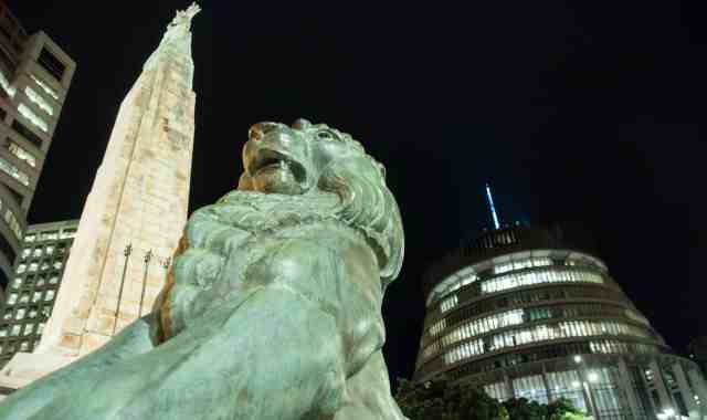 A nighttime shot with cenotaph in the foreground, with the lit up beehive behind.