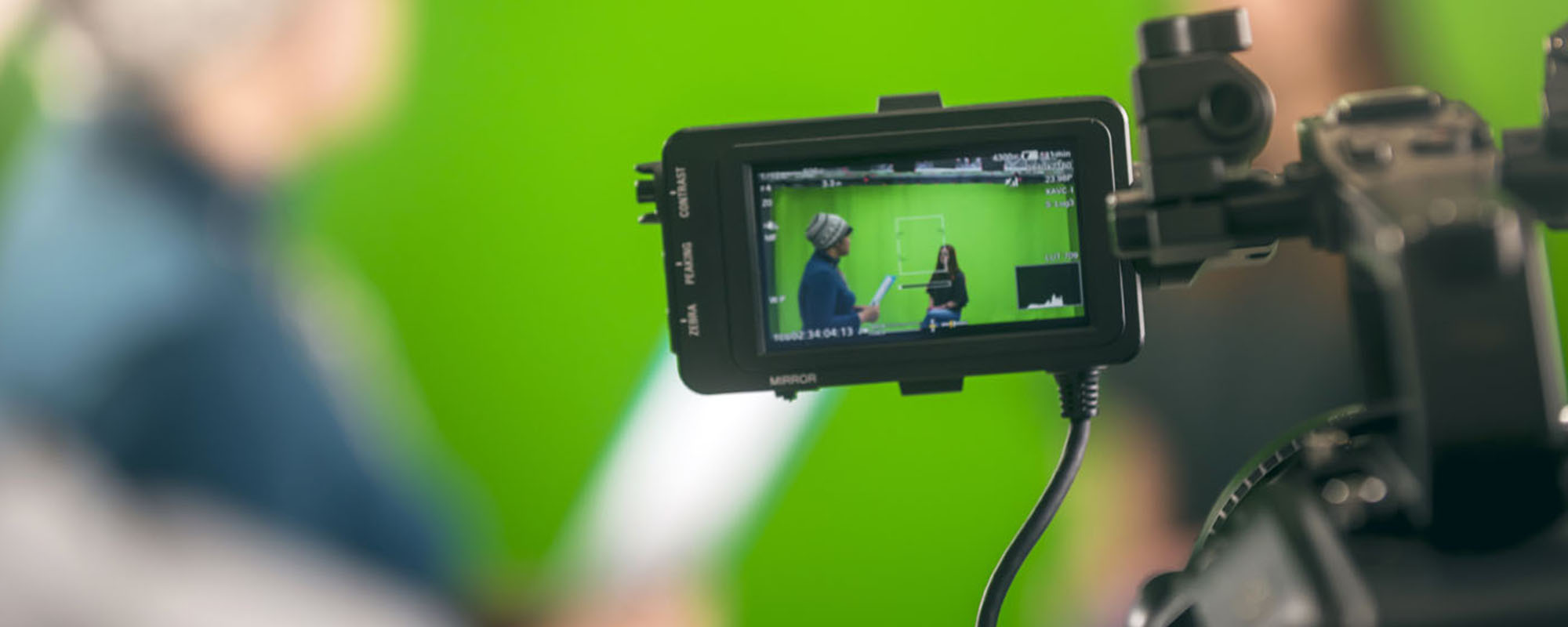 Film – A camera monitor shows two students working in front of a green screen.