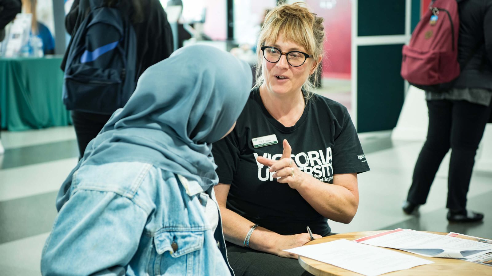 Blonde female careers consultant discussing a CV with Hijabi student in denim jacket