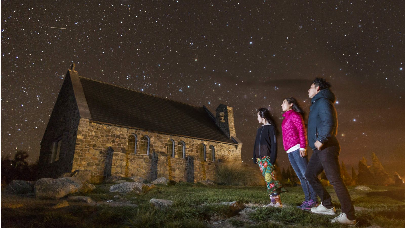 Image of three tourists stargazing at Church of the Good Shepard,Lake Tekapo, Canterbury