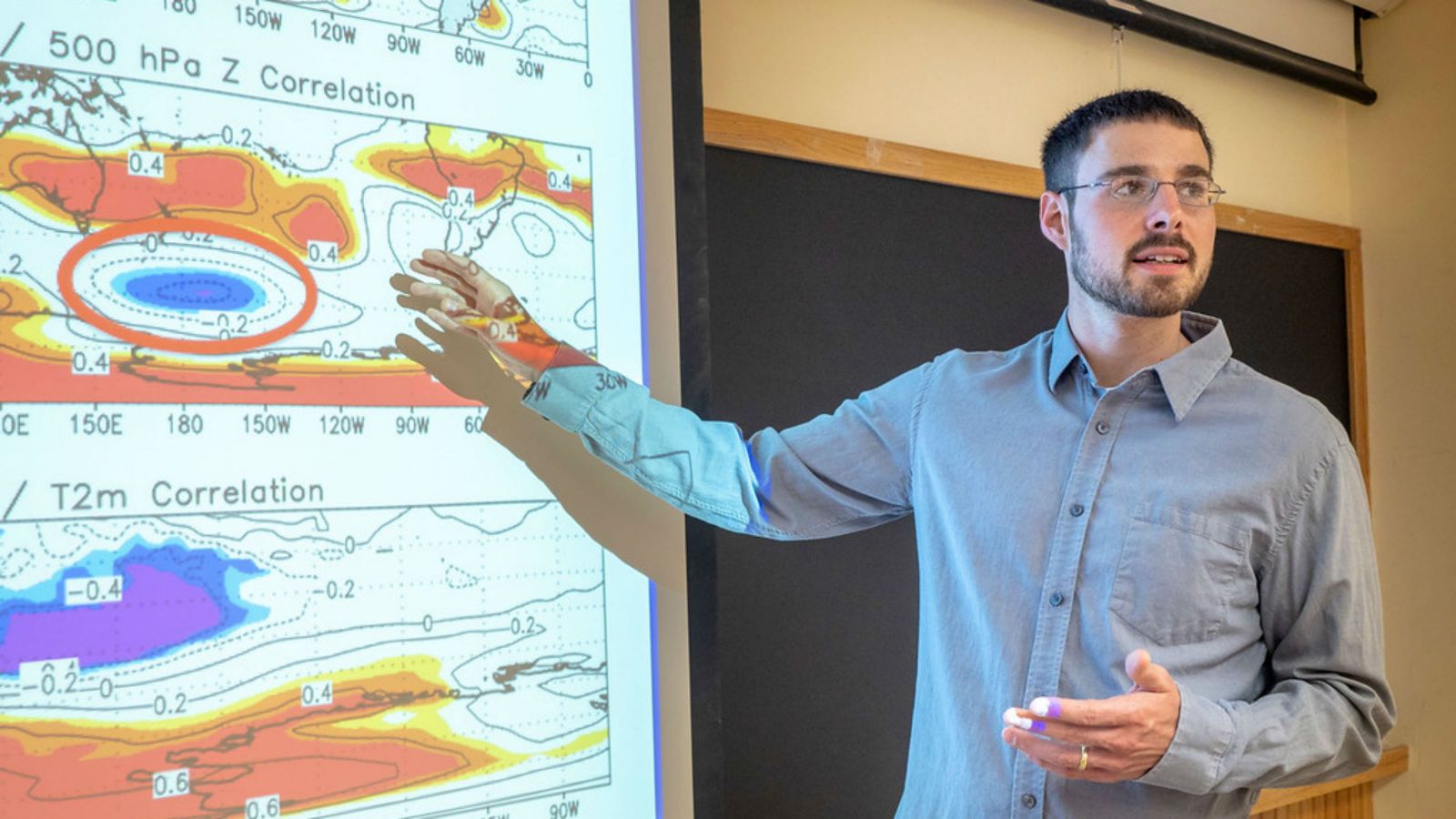 Kyle Clem stands in front of a map showing weather and pressure zones. 