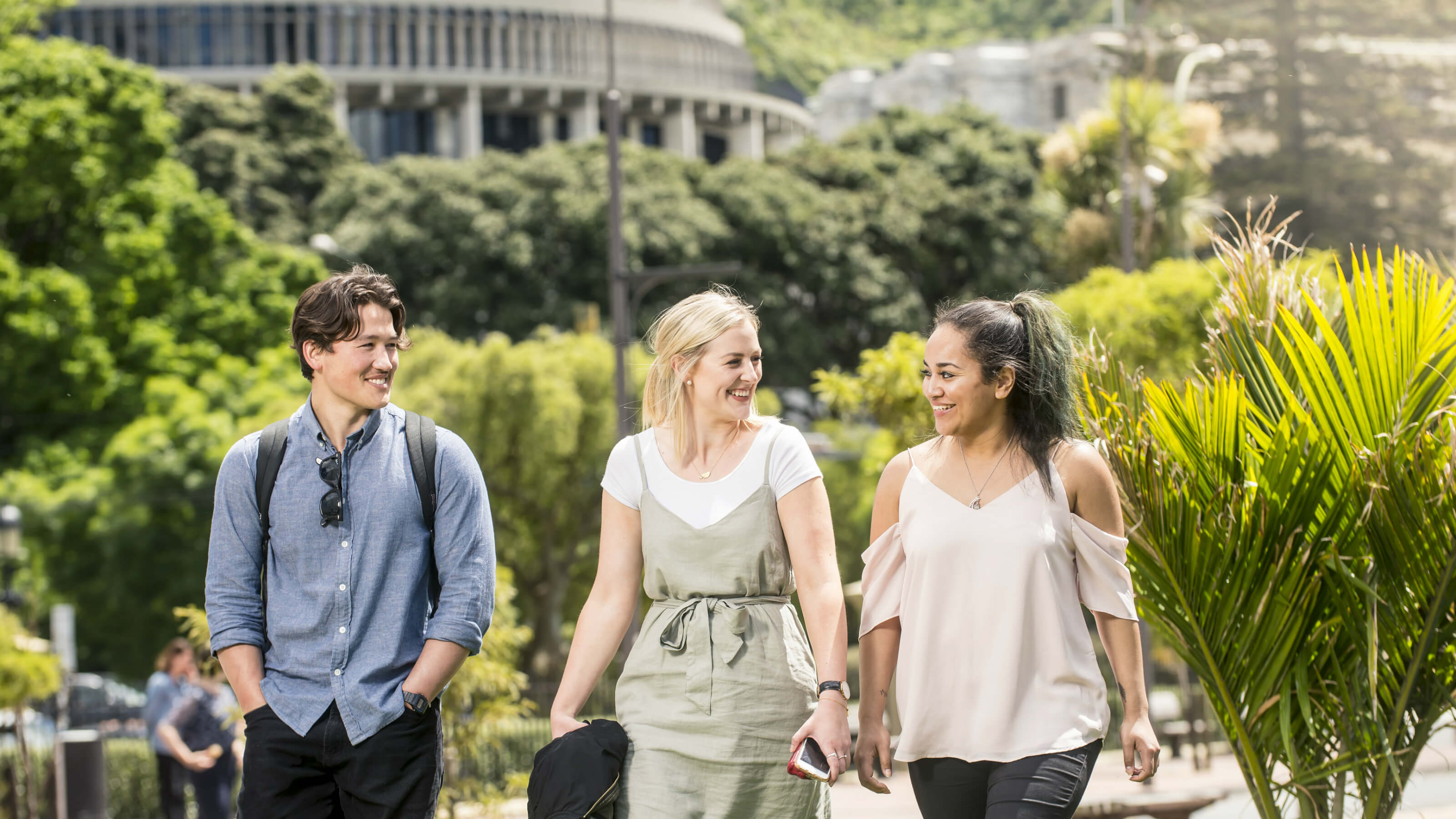 Three students walking past the Beehive, Parliament Buildings, in Wellington.