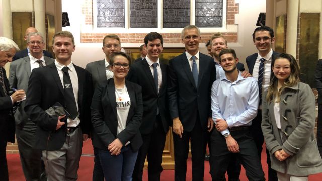 NATO officials, David Capie, and guests pose in a group.