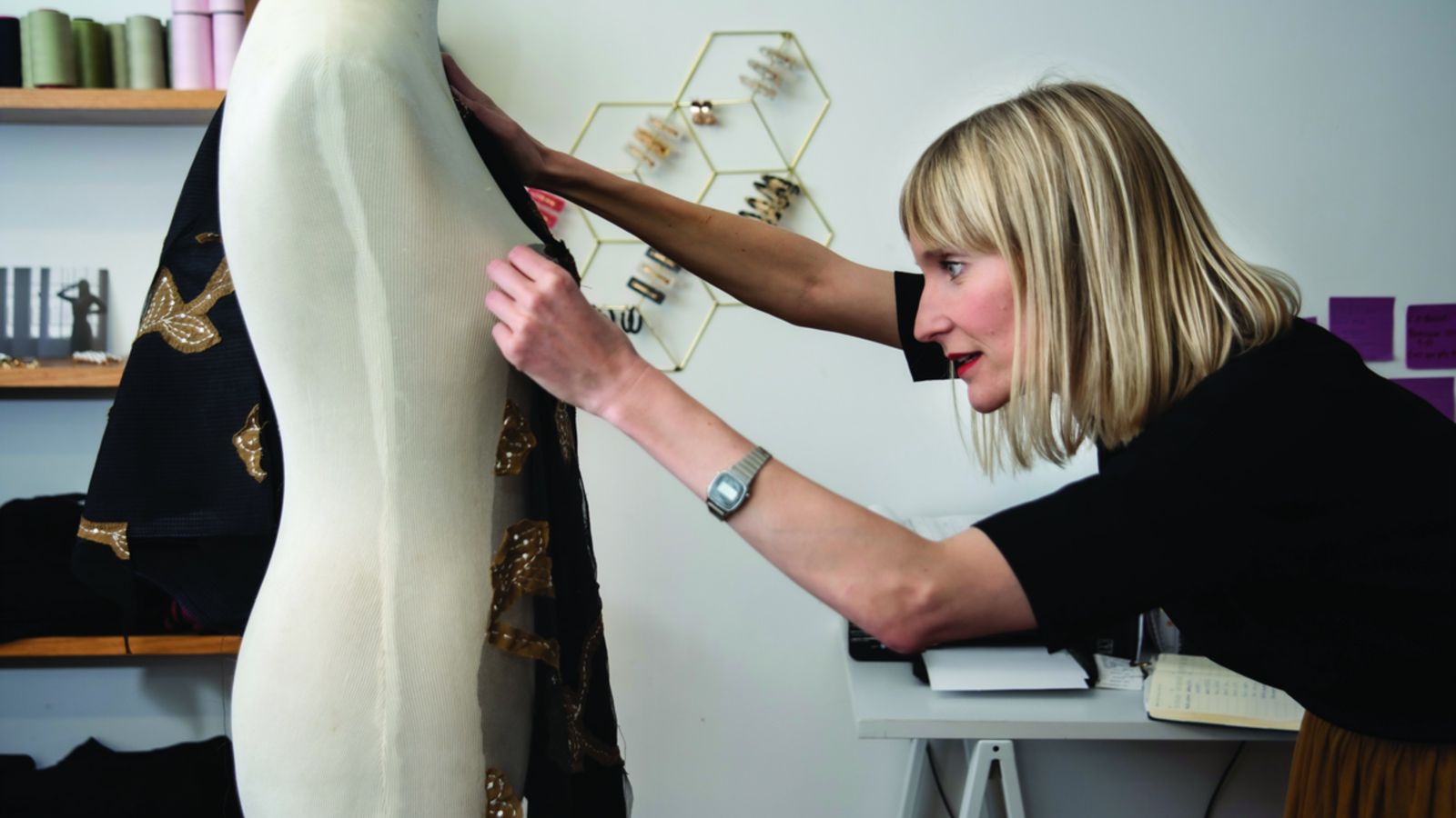 Hannah Goldblatt measures a piece of cloth for fit, against a female manikin.