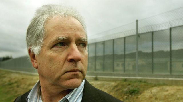 Roger Brooking in the foreground with a tall wire fence in the background that fades into the distance.