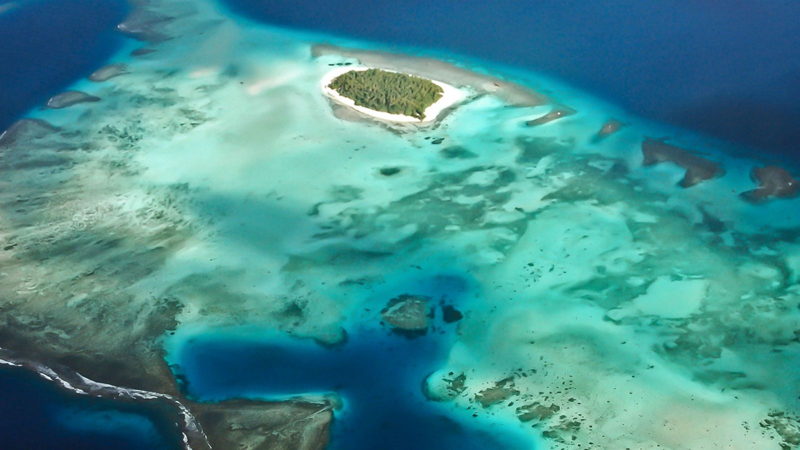An image of an island with a reef and surrounded by ocean, taken from above