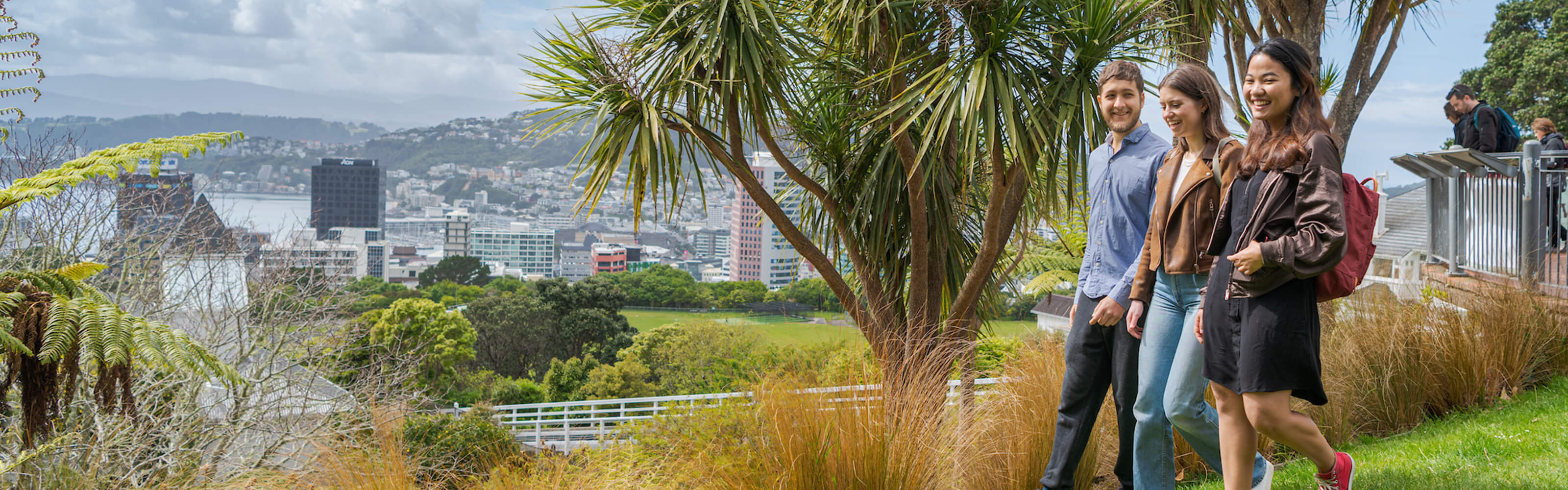 Students exploring Botanical garden with Wellington city view in background.