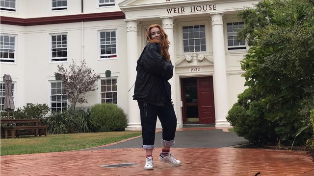 Ella stands outside of Weir House, an old white estate.