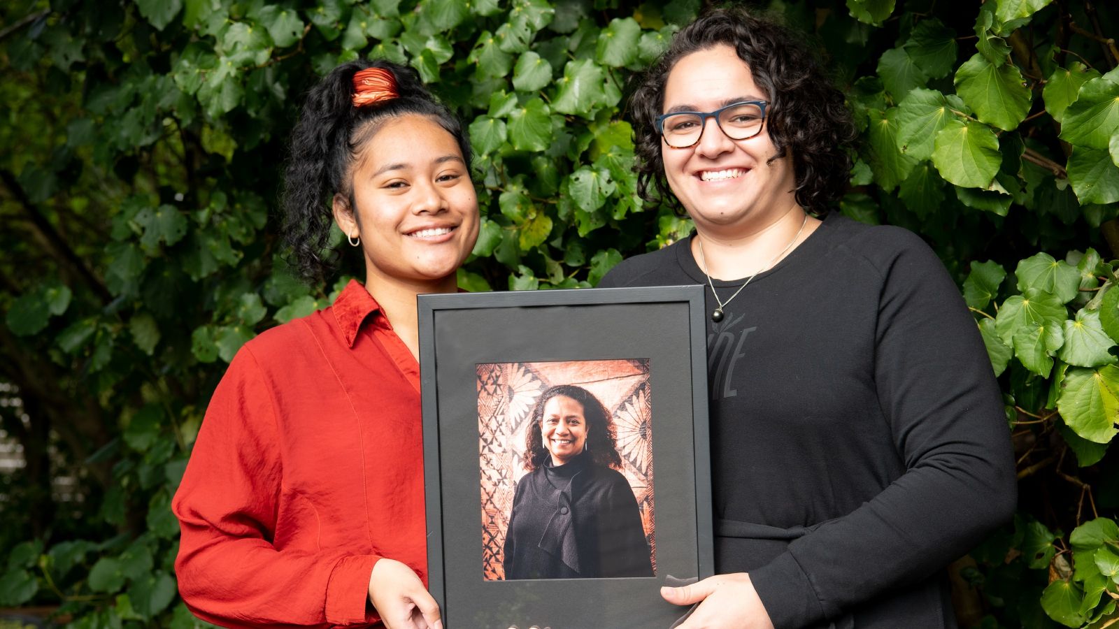 Kaitlin Abbot and Esther Patu, the two scholarship recipients, holding a framed picture of Teresia Teaiwa 