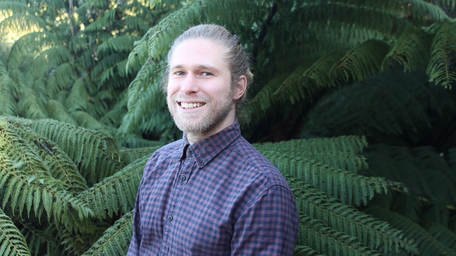 Jesse Kearse stands in front of ferns.