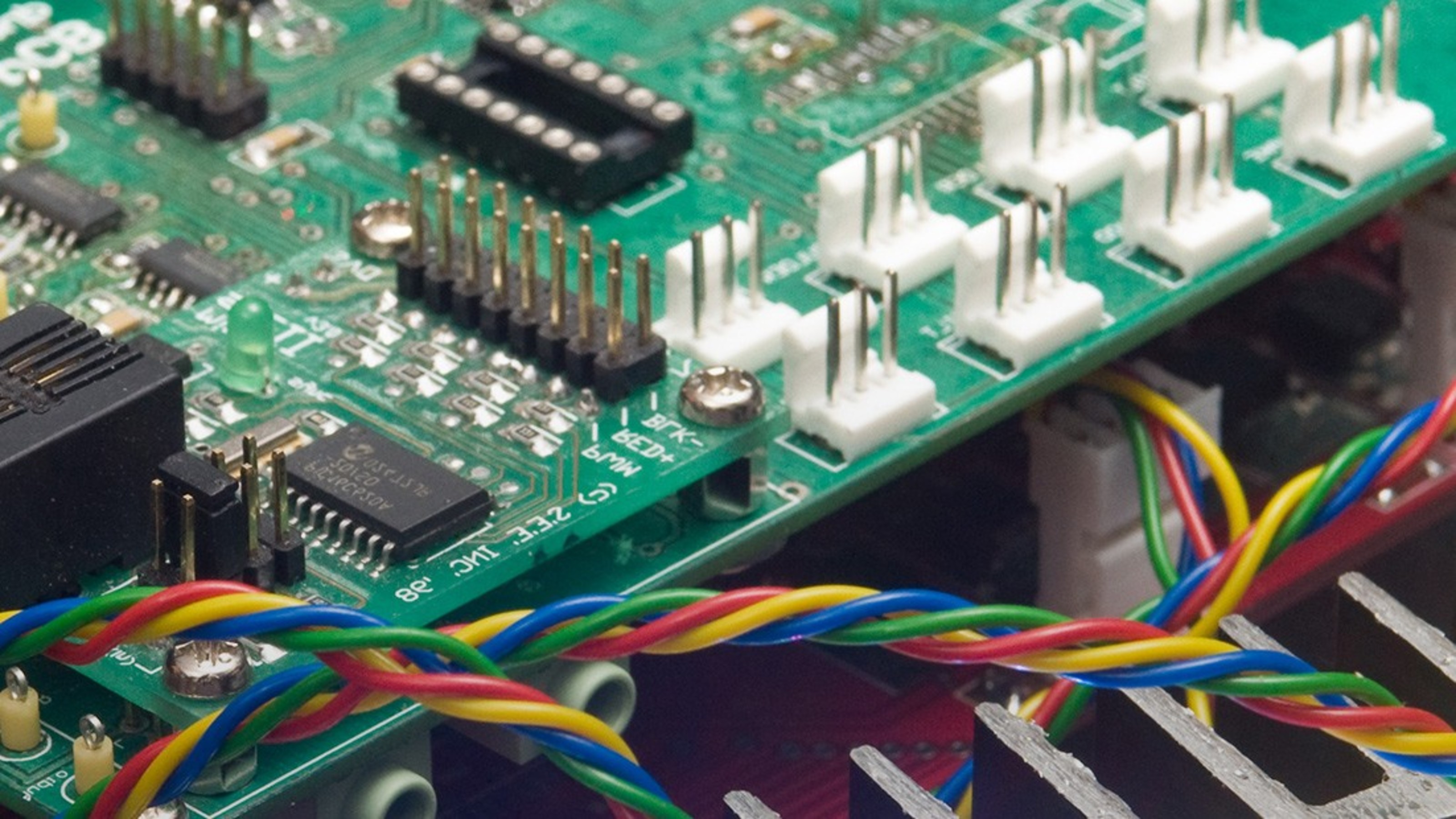 Close up image of a computer circuit board with coloured wires in the foreground.